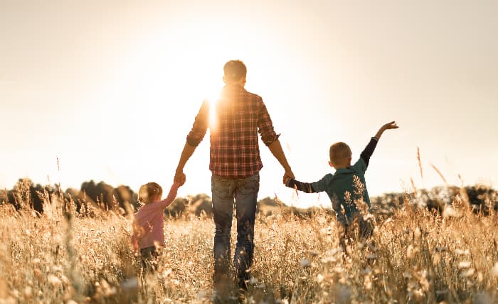 man and children walk through field holding hands working with grief counseling for loss